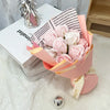 A bouquet of pink and white artificial roses wrapped in peach paper sits next to a book.