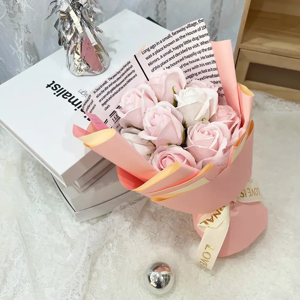 A bouquet of pink and white artificial roses wrapped in peach paper sits next to a book.