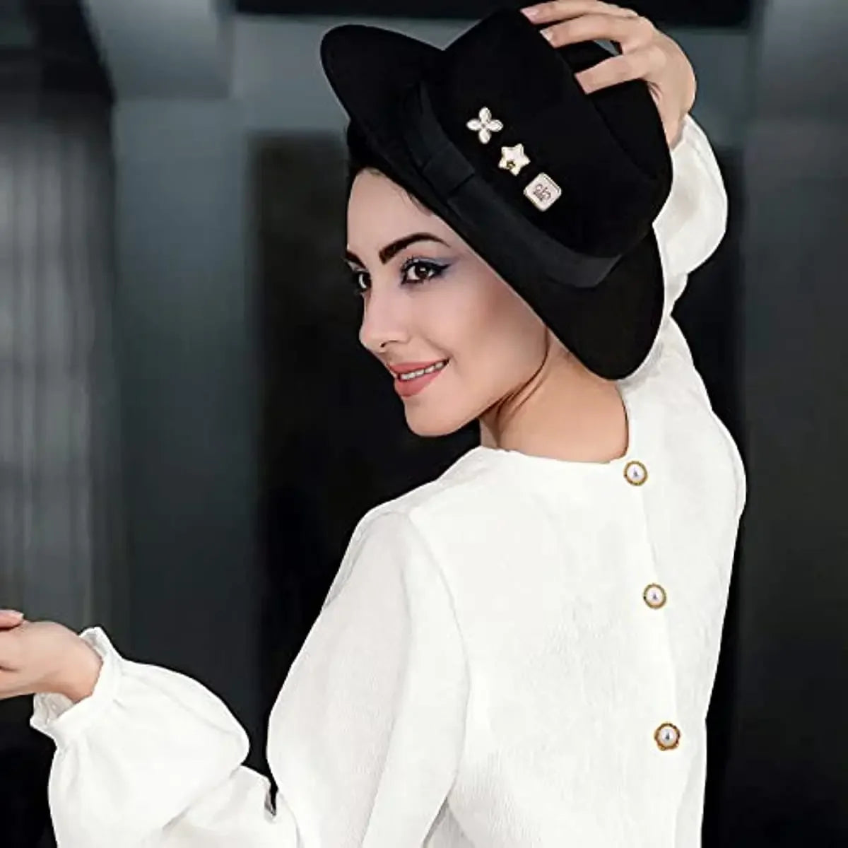 A woman models a white shirt and black hat adorned with pearl and rhinestone no-sew buttons.