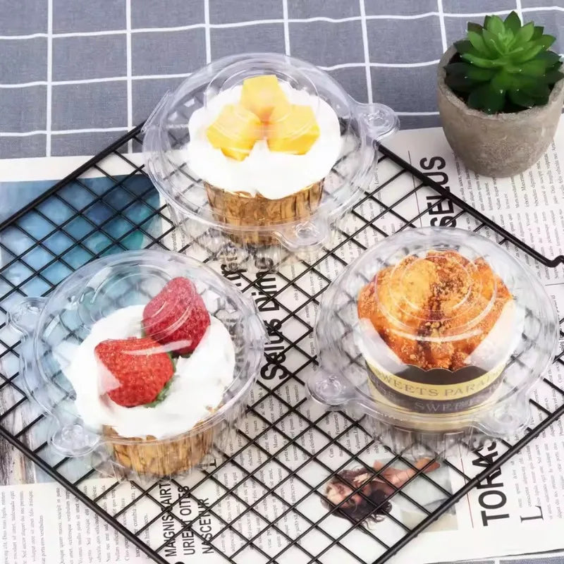 A clear plastic cake box with a lid containing a yellow cake on a black wire rack.