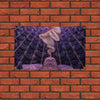 A tapestry featuring a pattern of many eyes and a face emerging from the center, displayed against a brick wall.