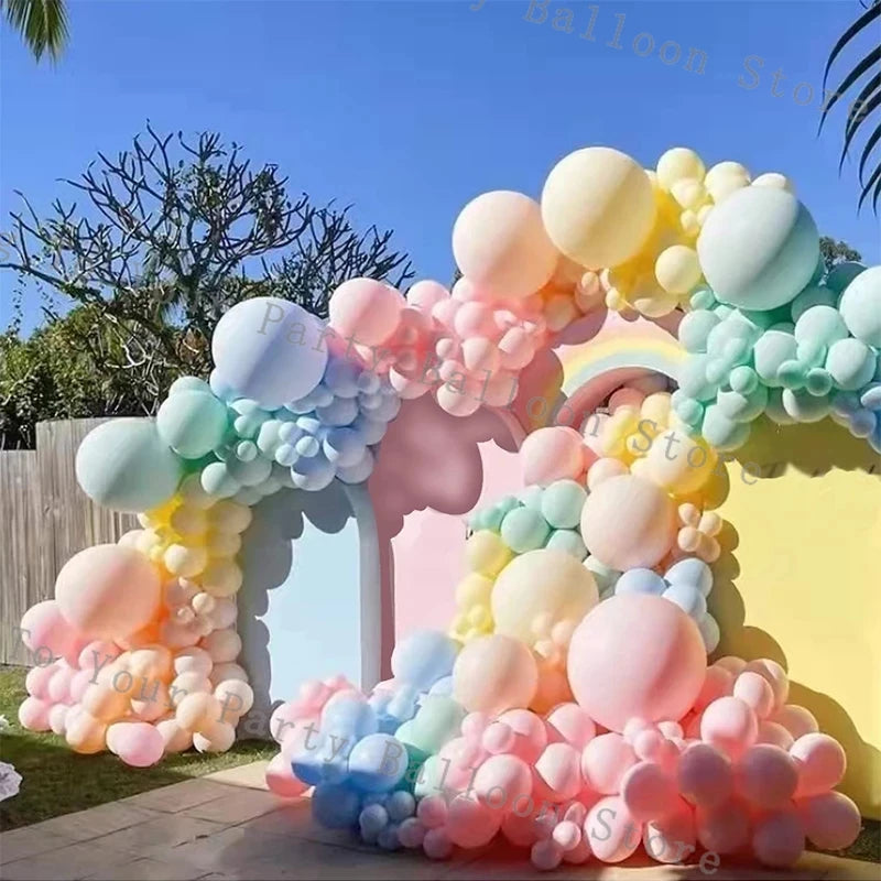 A colorful balloon garland arch made of pastel pink, blue, and yellow balloons for a party decoration.