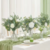 A centerpiece display of mixed eucalyptus and willow artificial flower bouquets on a white table setting.