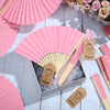 Pink paper hand fans with thank you cards displayed in a box on a wooden surface.