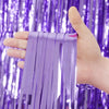 Une main tient des rideaux à franges arc-en-ciel violet sur un fond de sequins violets.
