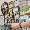 A person is assembling a rotating photo frame with 12 display slots made of dark metal and light-colored paper.