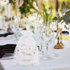 Elegant white and gold drawstring organza bags for gifts displayed on a table setting.