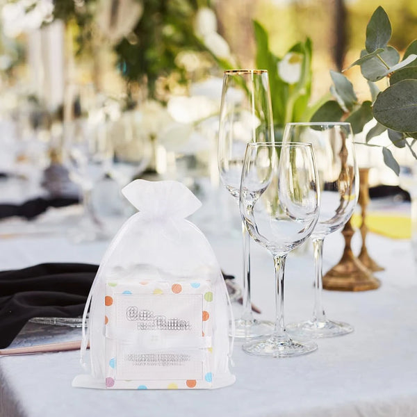 Elegant white and gold drawstring organza bags for gifts displayed on a table setting.