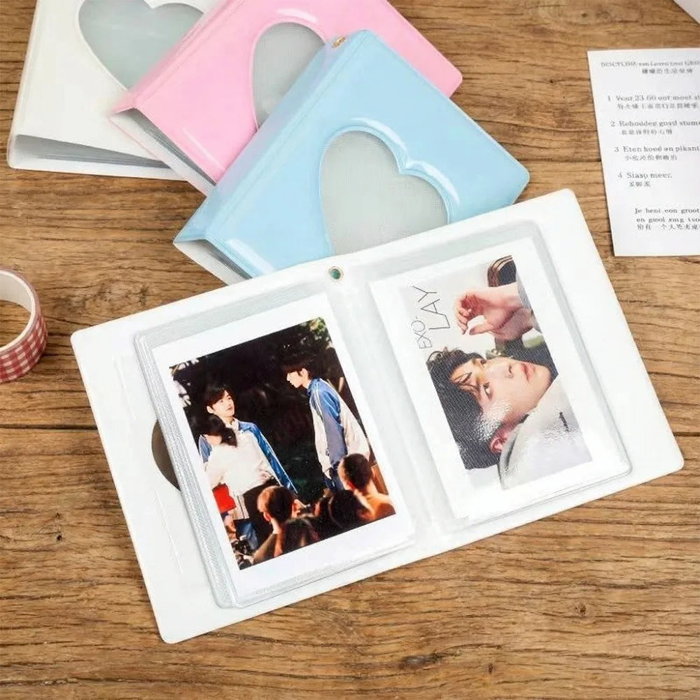 A white photo album with a heart-shaped cover and four pockets is displayed on a wooden surface.