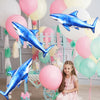 Blue shark foil balloons and a girl in a pink dress decorate an ocean-themed party setup.