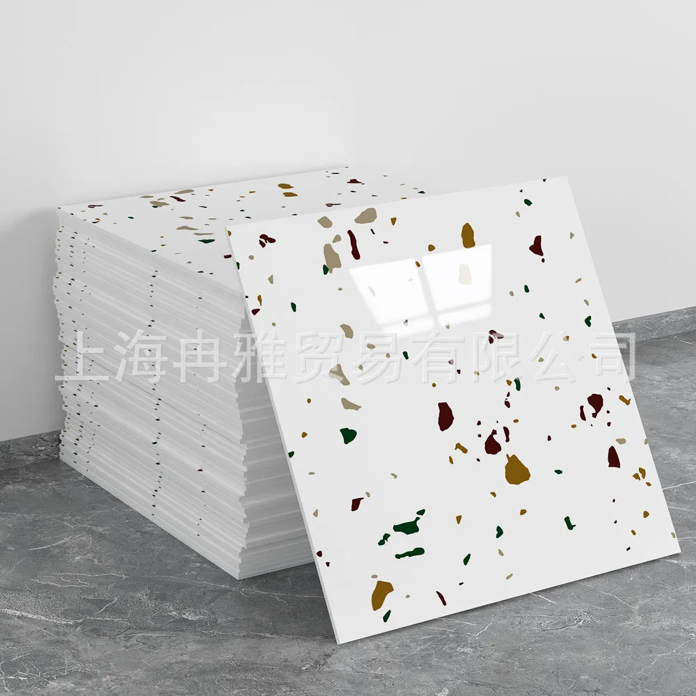 A stack of faux marble 3D self-adhesive wall tiles with multicolored flecks displayed on a gray surface.