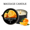 A black massage candle in a jar with an orange-scented wax and a sliced orange nearby.