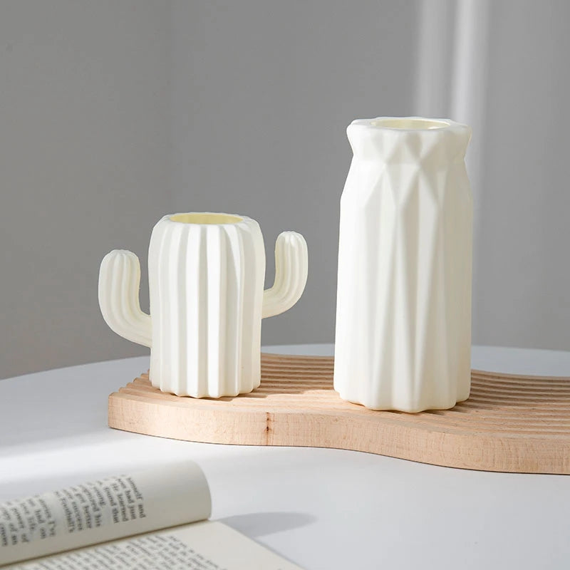 Weiße moderne Plastikblumenvase mit vertikalen Rillen auf einem hellen Holzbrett.
