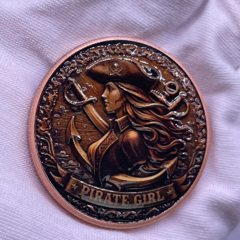 A copper challenge coin featuring a pirate girl design with flowing hair and an eyepatch.
