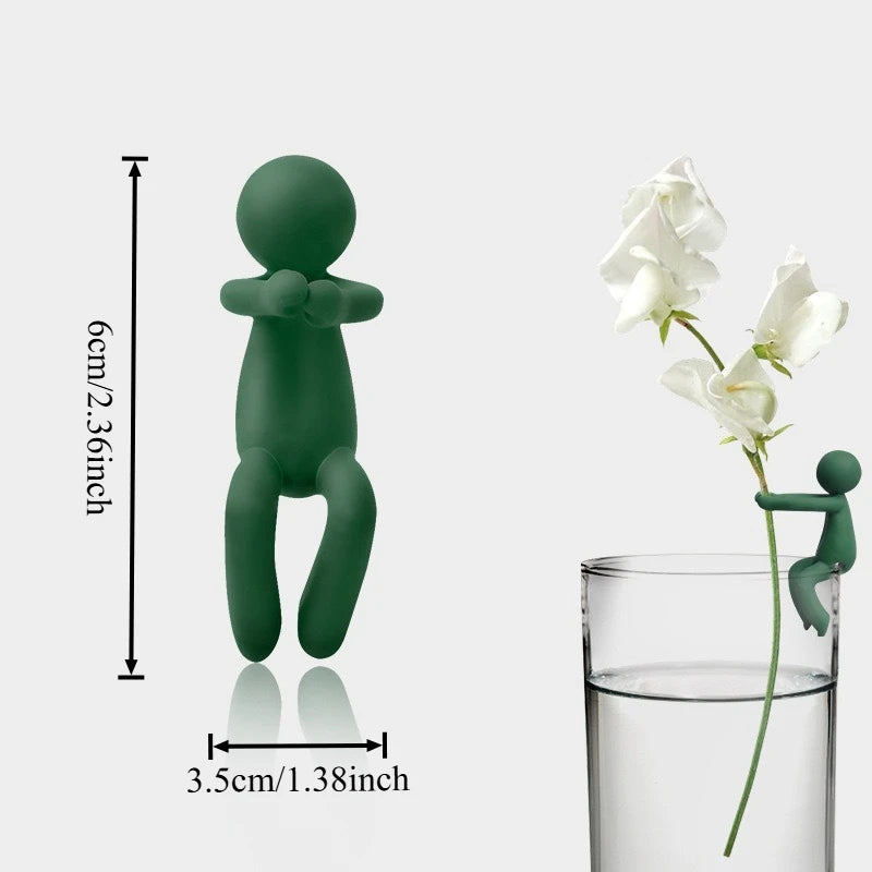 A set of three green human-shaped plant supports used for hydroponic growth, shown next to a glass.