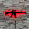 A red LED gun-shaped wall decor light mounted on a gray stone brick wall.