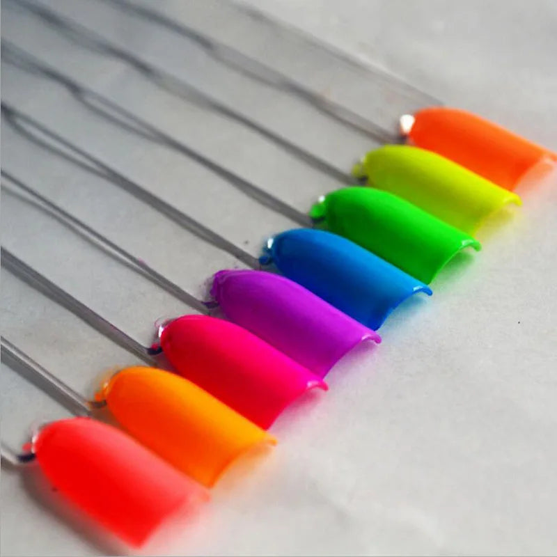 A set of thirteen vivid neon fluorescent pigment powders arranged in a row on a white surface.