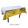 Una mesa de fiesta desechable rectangular dorada cubierta con tela de lunares blancos y decoraciones de cumpleaños.
