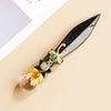 A decorative piece featuring an obsidian blade with gold accents and a large amethyst crystal ball.