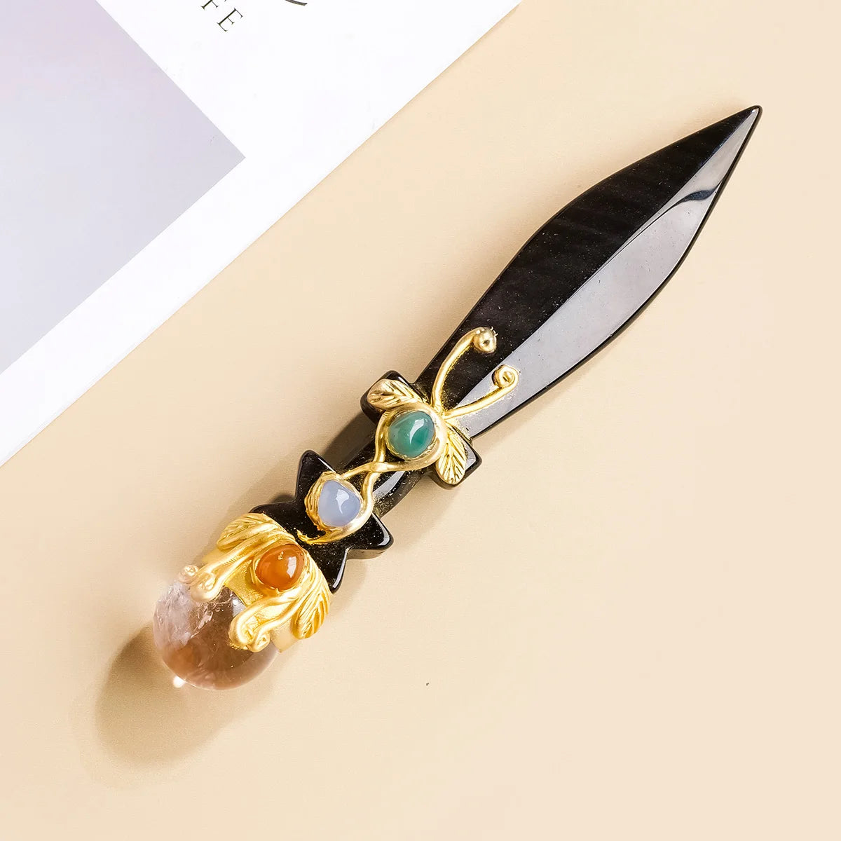 A decorative piece featuring an obsidian blade with gold accents and a large amethyst crystal ball.