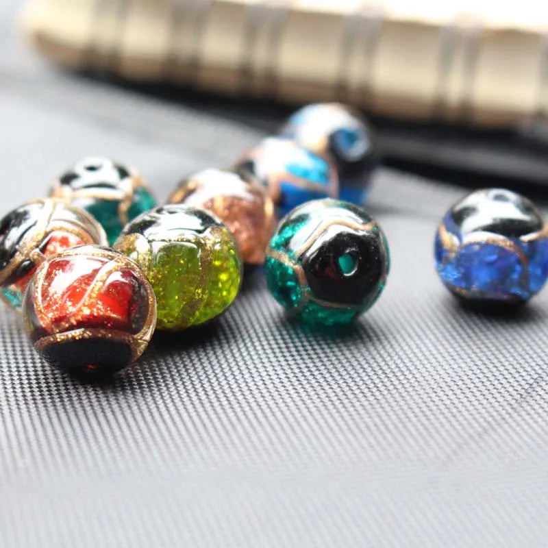 A collection of handcrafted lampwork glass beads with gold accents scattered on a dark surface.