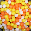 A large pile of colorful, round plastic balls in shades of orange, yellow, and white.
