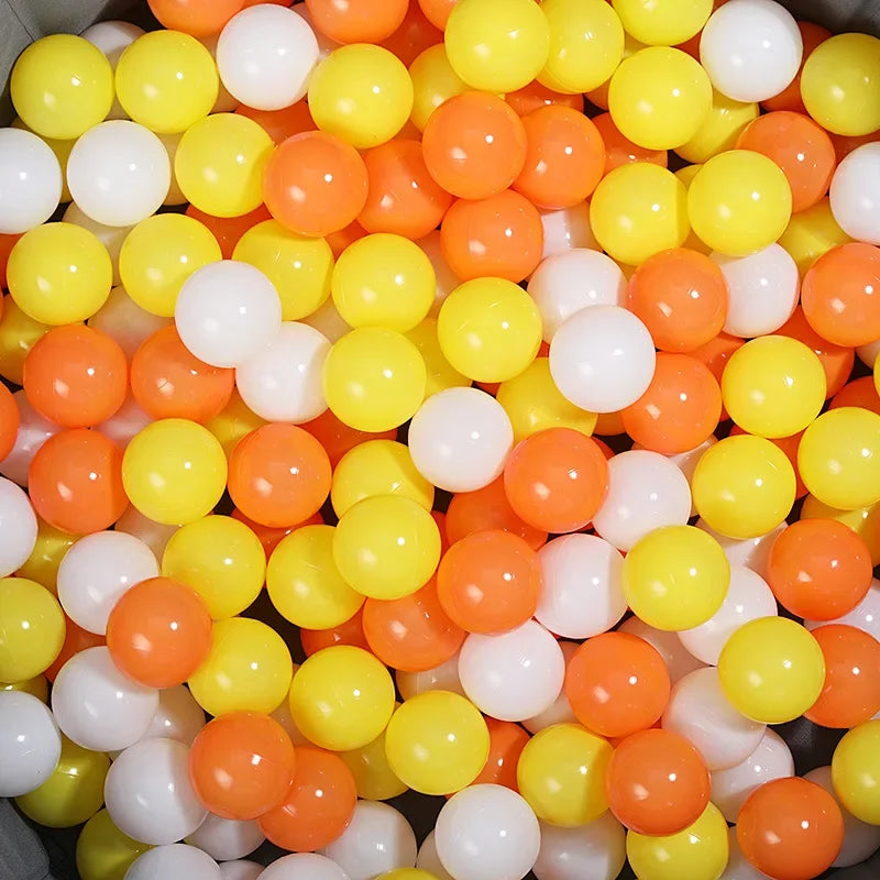 A large pile of colorful, round plastic balls in shades of orange, yellow, and white.