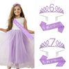 A young girl wearing a purple tulle dress and a purple tiara crown sash set for her birthday