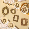 A collection of miniature vintage gold picture frames and pearl beads arranged on a light beige surface.