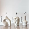Three white ceramic geometric vases of varying heights displayed on a white surface.