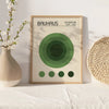 A framed art print featuring the Bauhaus logo and concentric circles in shades of green, displayed on a white surface.