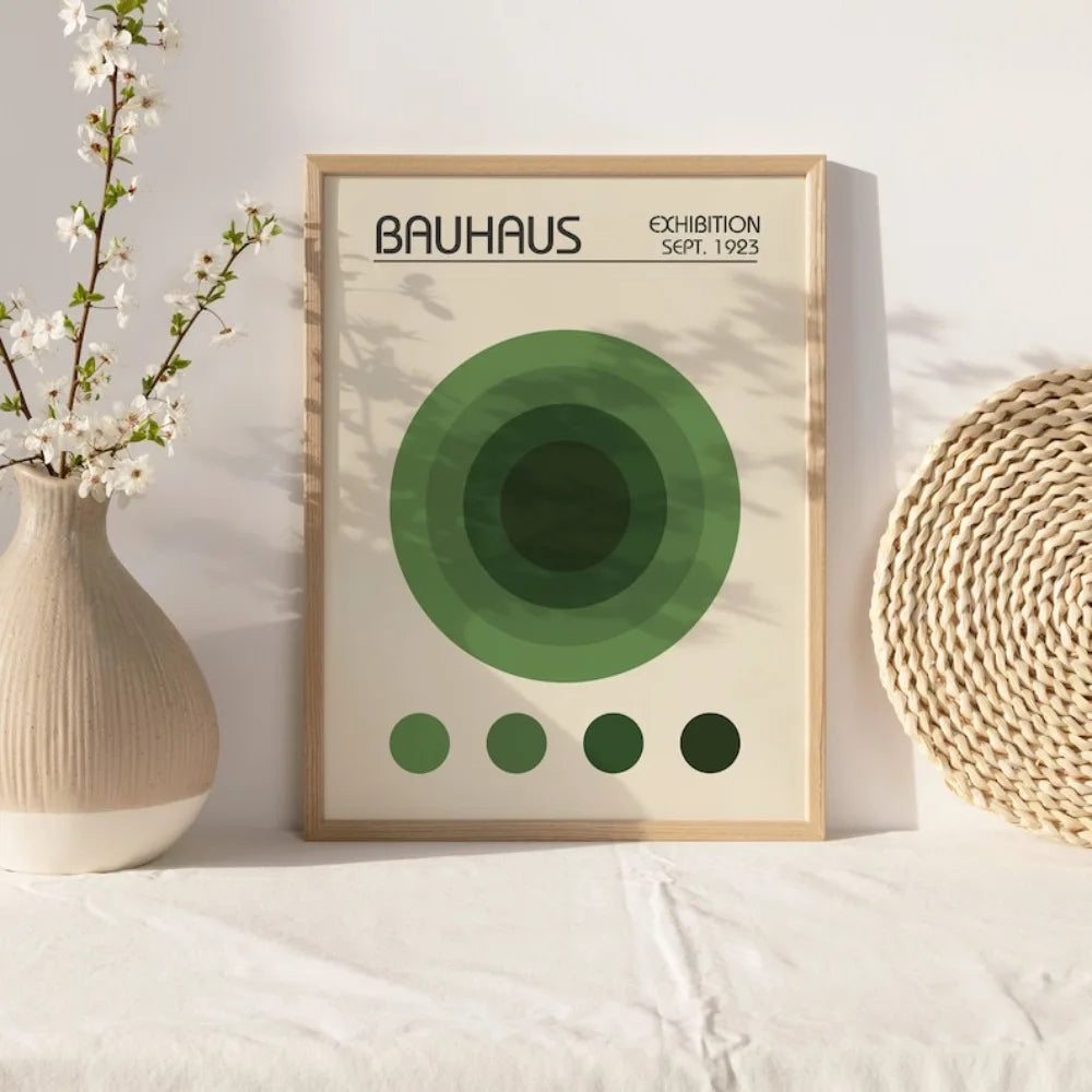 A framed art print featuring the Bauhaus logo and concentric circles in shades of green, displayed on a white surface.
