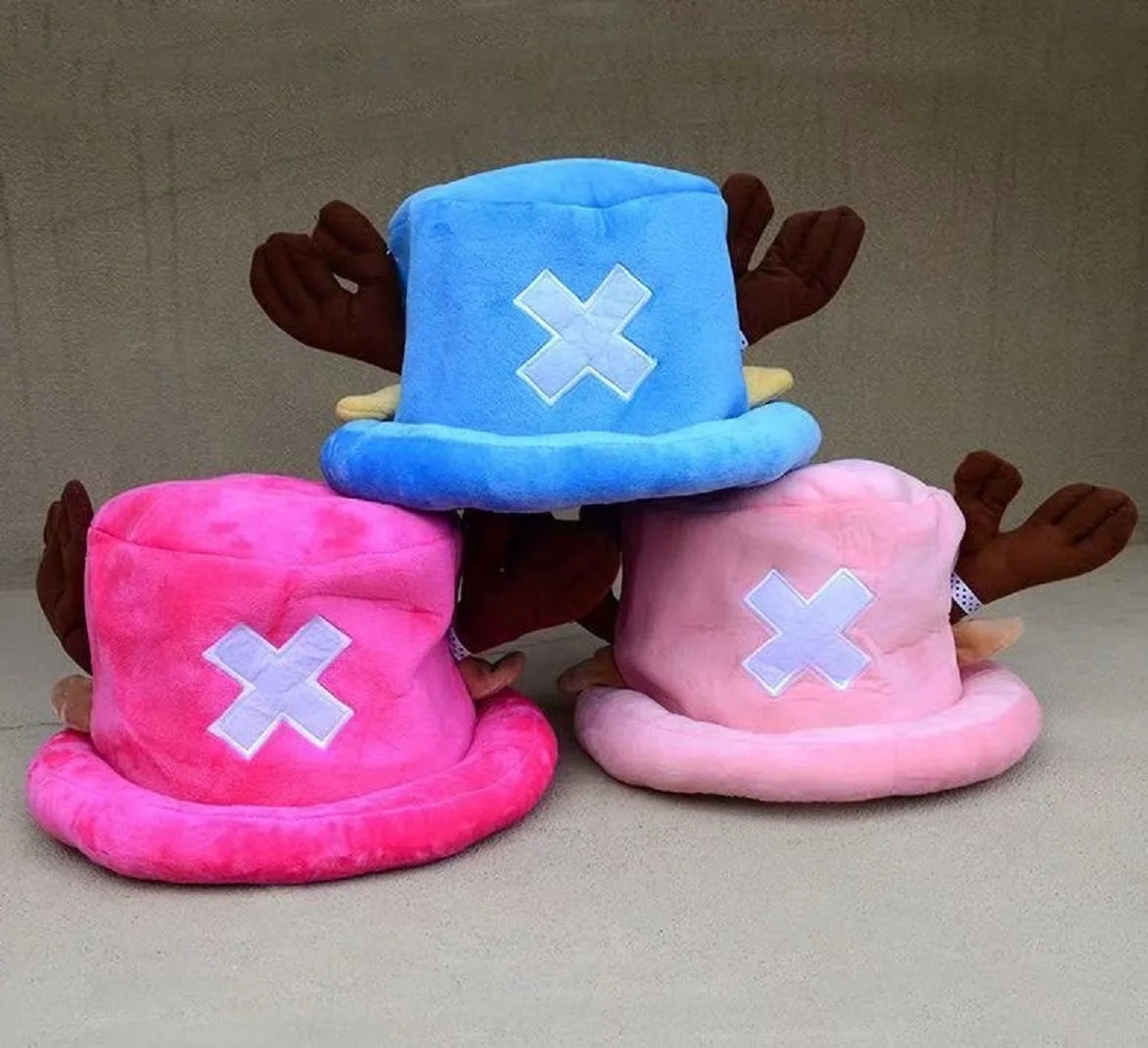 A pair of plush knit hats in blue and pink with white crosses, resembling Tony Tony Chopper.