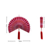 Handwoven bamboo wall fan decor in pink and red stripes with a tassel.