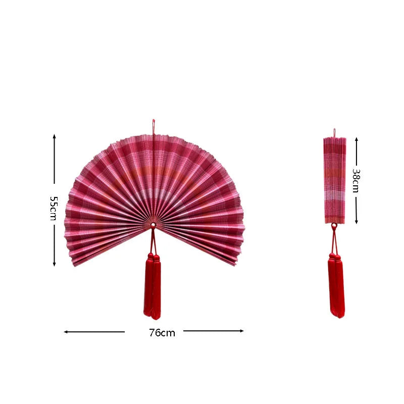 Handwoven bamboo wall fan decor in pink and red stripes with a tassel.