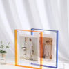 Zwei moderne Acryl-Foto-Displayrahmen, einer orange und einer blau, auf einer weißen Oberfläche.