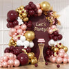 A balloon garland arch featuring burgundy, gold, and white balloons arranged in a decorative display.