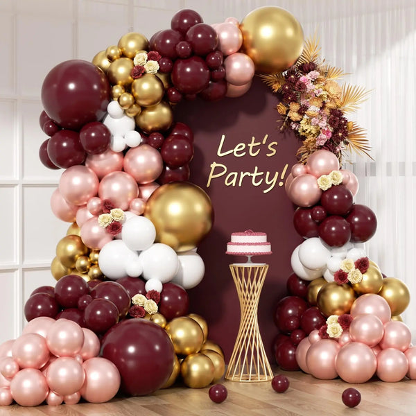A balloon garland arch featuring burgundy, gold, and white balloons arranged in a decorative display.