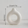A white modern ceramic circular vase with a smooth, organic shape.