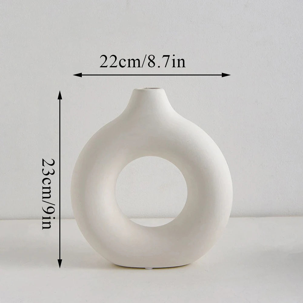 A white modern ceramic circular vase with a smooth, organic shape.