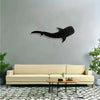 Black silhouette of a whale shark with white polka dots mounted on a gray wall above a beige sofa and patterned rug.