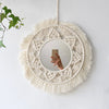 Miroir rond en macramé mural avec une couronne de fibres naturelles et un miroir circulaire suspendu sur un mur blanc.
