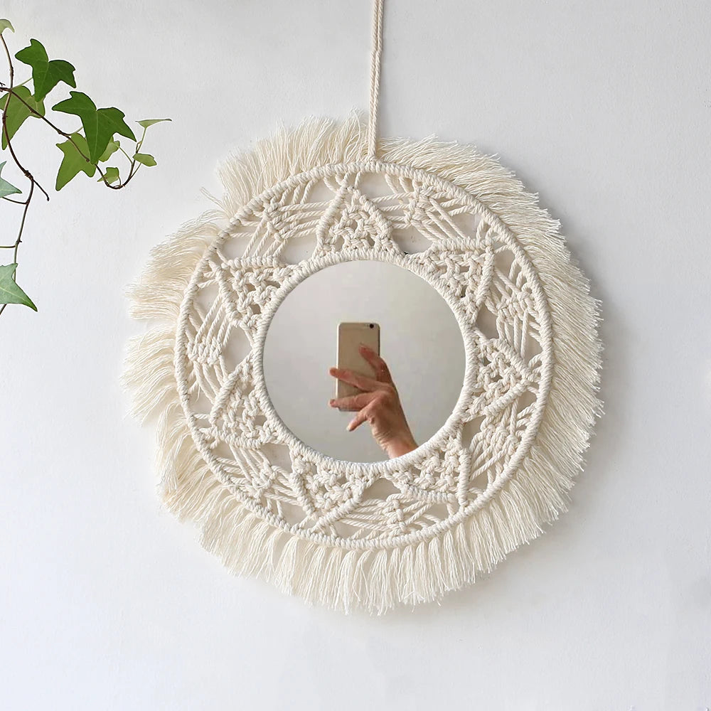 Miroir rond en macramé mural avec une couronne de fibres naturelles et un miroir circulaire suspendu sur un mur blanc.