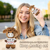 A smiling young woman holds a brown crochet cow doll with a thank you message card.