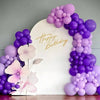 A large white sign decorated with gold text Happy Birthday surrounded by a purple latex balloon arrangement.