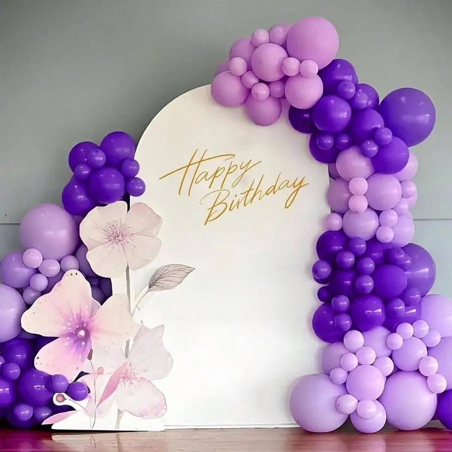 A large white sign decorated with gold text Happy Birthday surrounded by a purple latex balloon arrangement.