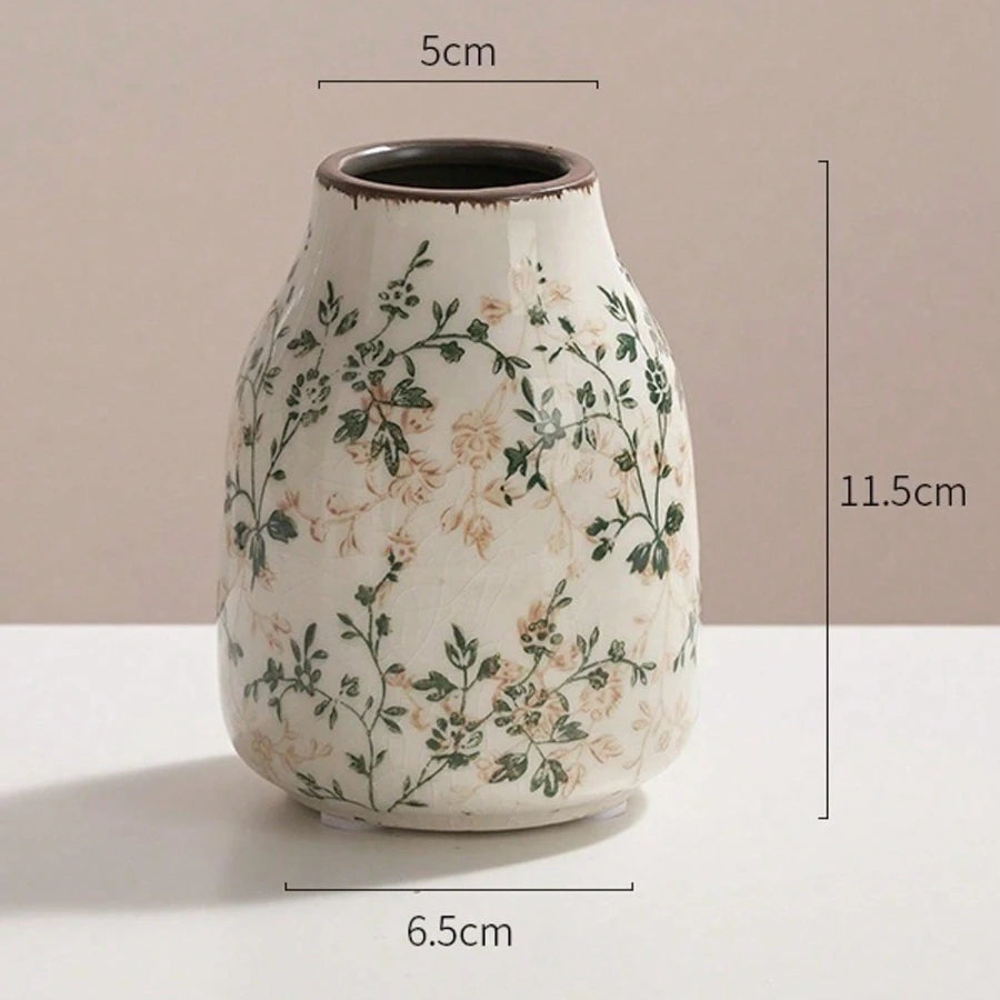A handmade ice crackle ceramic vase with a speckled white glaze and green floral pattern.
