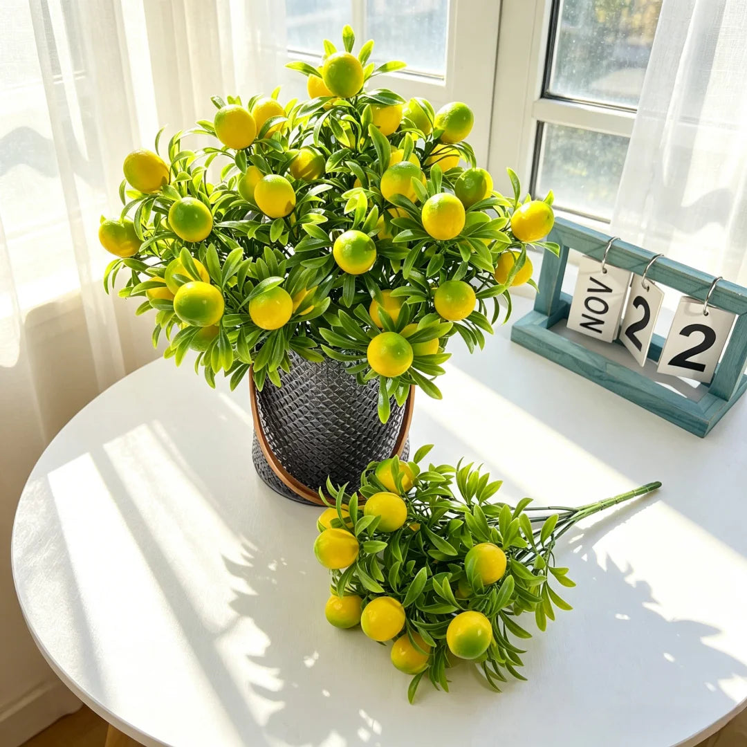A bouquet of four artificial lemon branch stems with bright yellow fruit displayed on a white table.