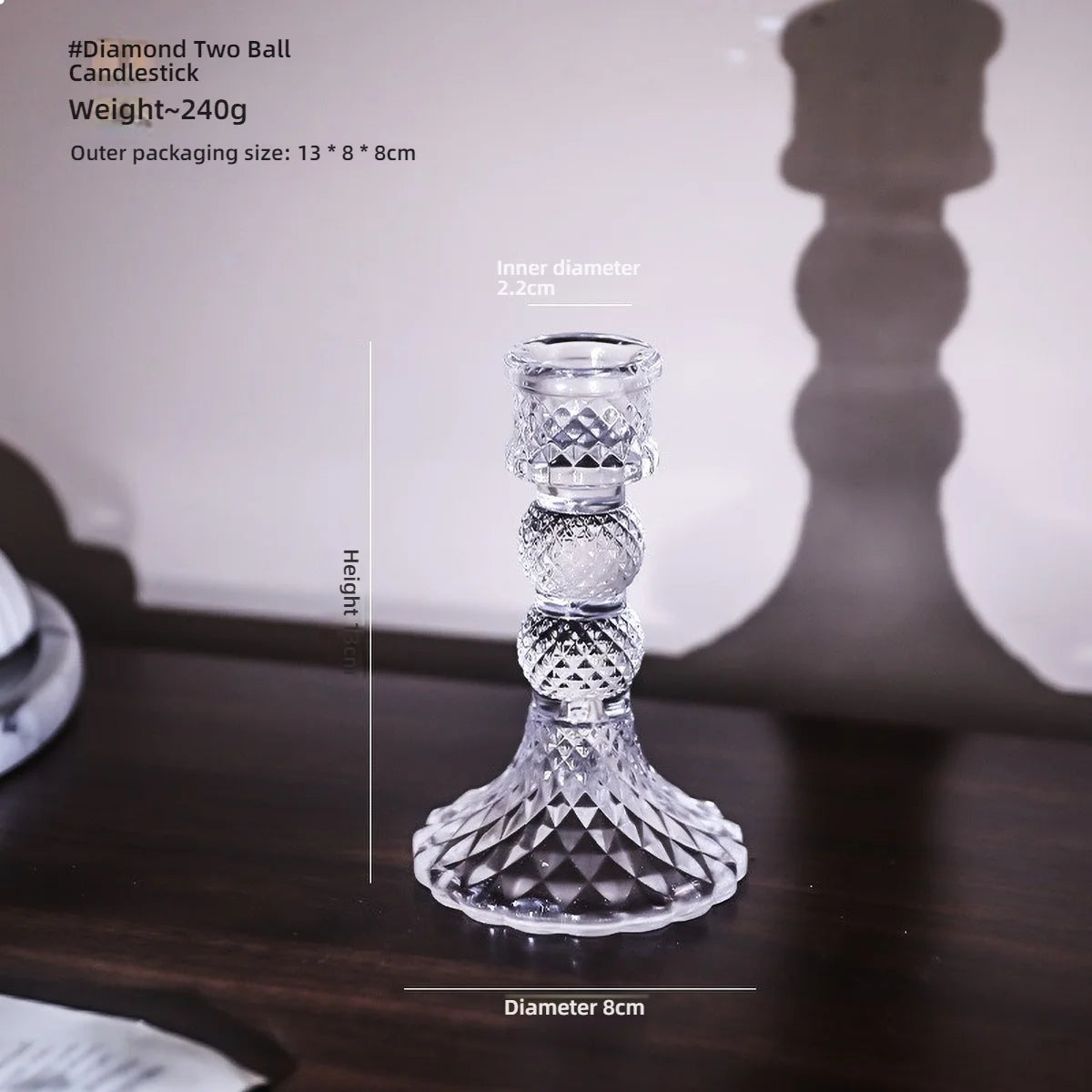 A clear glass pillar candle holder with an ornate design, shown against a dark background.