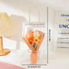 A clear plastic bag containing a handmade crochet flower bouquet wrapped in orange paper and tied with twine.